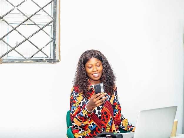 Junge schwarze Frau sitzt im Café und benutzt Smartphone mit ihrem Handy