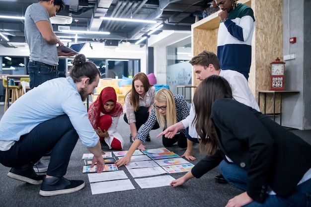 junge schwarze muslimische geschäftsfrau, die sich mit ihrem multiethnischen startup-business-team in einem modernen bürointerieur trifft und neue ideen auf dem boden präsentiert