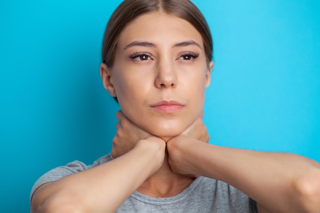 Junge schwermütige junge Frau, die ihren Hals hält