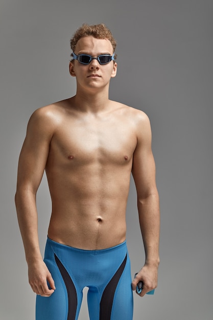 Junge Schwimmer in ausgezeichneter körperlicher Verfassung, auf grauem Hintergrund mit Kopienraum, Aufruf zum Sport, Werbebanner.