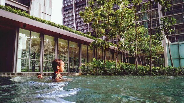 Foto junge schwimmt im pool gegen ein gebäude