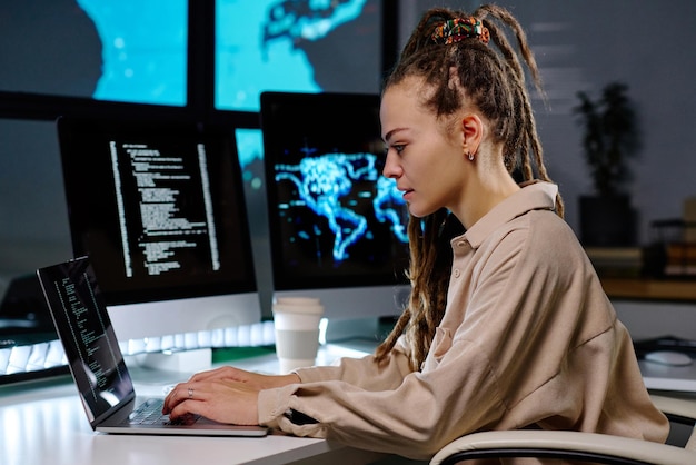 Junge seriöse IT-Managerin, die im Büro auf der Laptop-Tastatur tippt