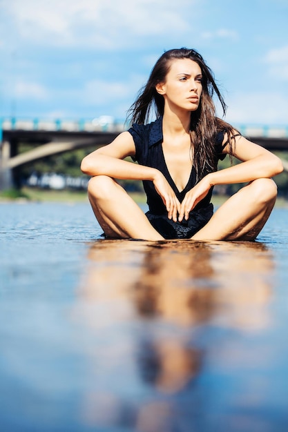 Junge sexy Frau, die im Wasser sitzt