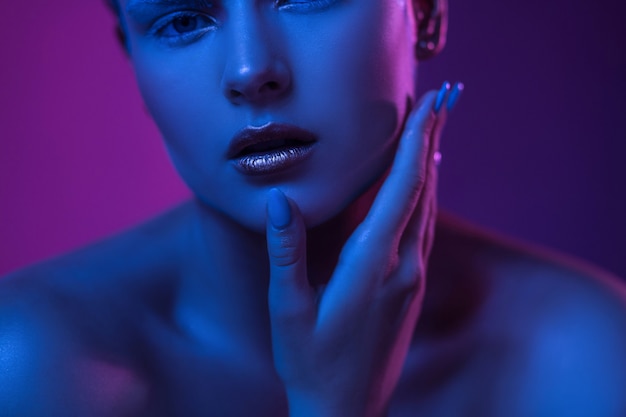 Junge sexy Frau mit offenen Lippen in lila blauen Neonlichtern.