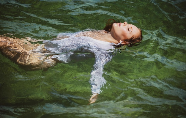 Junge sexy Frau schwimmt im transparenten blauen Meer sinnliche schlanke Frau, die auf dem Wasser schwimmt