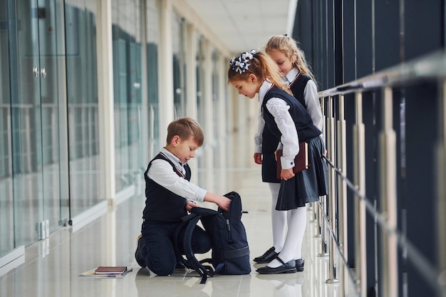 Junge sitzt auf dem Boden Schulkinder in Uniform zusammen im Korridor