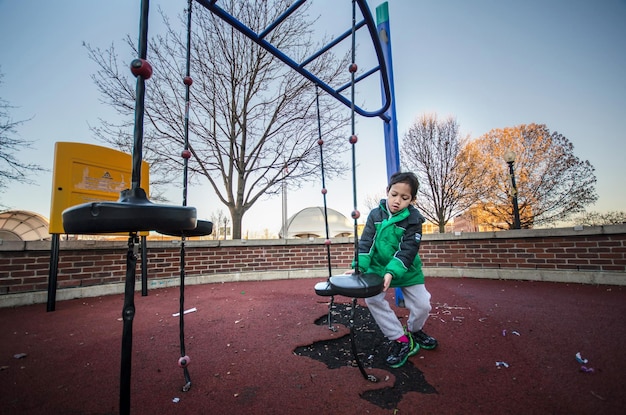 Foto junge sitzt auf einem spielgerät im freien auf dem spielplatz