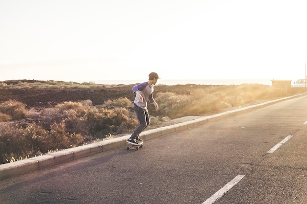 Junge skateboardet in voller Länge auf der Straße gegen klaren Himmel