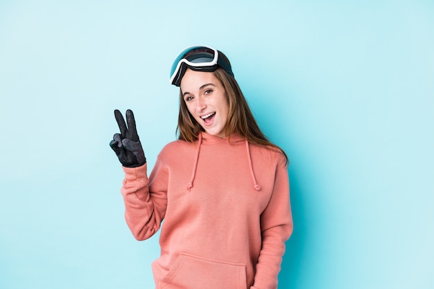 Junge Skifahrerfrau lokalisiert fröhlich und sorglos, ein Friedenssymbol mit den Fingern zeigend.