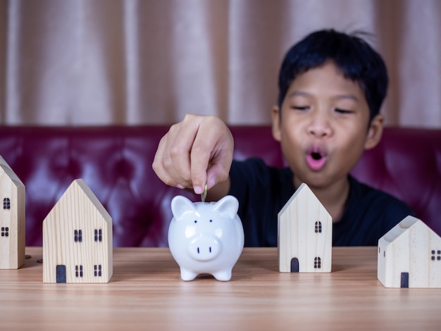 Junge spart Geld in einem weißen Sparschwein. Sparkonzept. Sparen für die Zukunft.