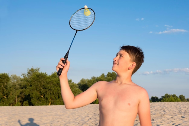 Junge spielt Badminton am Strand an einem sonnigen Tag Sport Sommerspiele im Urlaub gesunder Lebensstil