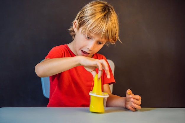 Junge spielt handgemachtes Spielzeug namens Slime Child Play mit Slime Kid Squeeze und Stretching Slime