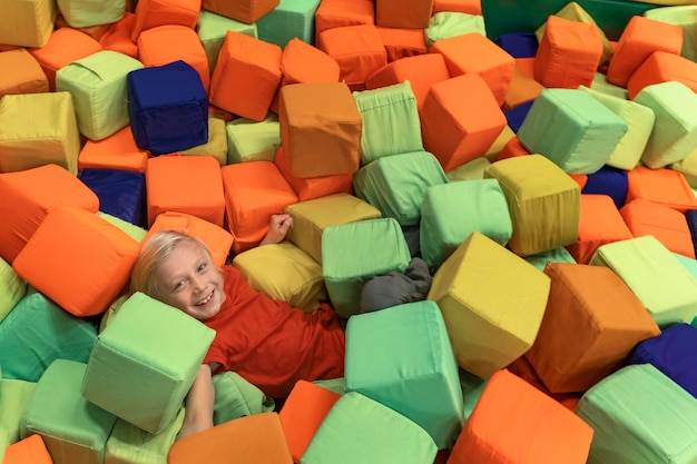 Junge spielt im Kinderspielzimmer herum Weiche Würfel für Spiele Kind hat Spaß in einem Unterhaltungszentrum