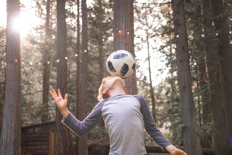 Foto junge spielt im park mit einem fußball