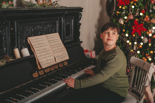 Junge spielt Klavier in Weihnachtsschmuck