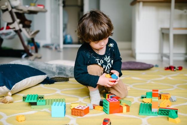 Junge spielt mit Bausteinen zu Hause auf dem Boden