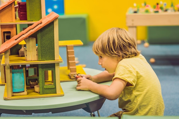 Junge spielt mit Holzhaus im Kindergarten