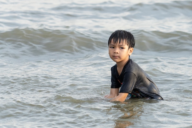 Junge spielt mit Sand und Welle am Strand