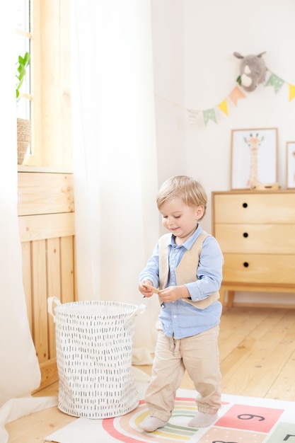 Junge spielt mit Spielzeug im Raum. Umweltfreundliche Kinderzimmerdekoration im skandinavischen Stil. Porträt eines Jungen, der im Kindergarten spielt. Kinderzimmer und Innenausstattung. Der Junge ist zu Hause.