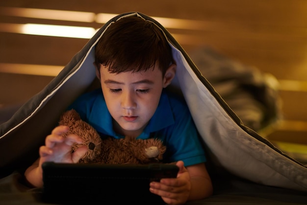 Junge spielt nachts auf dem Tablet