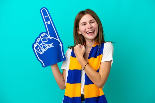 Junge Sportfanfrau lokalisiert auf blauem Hintergrund, der einen Sieg feiert