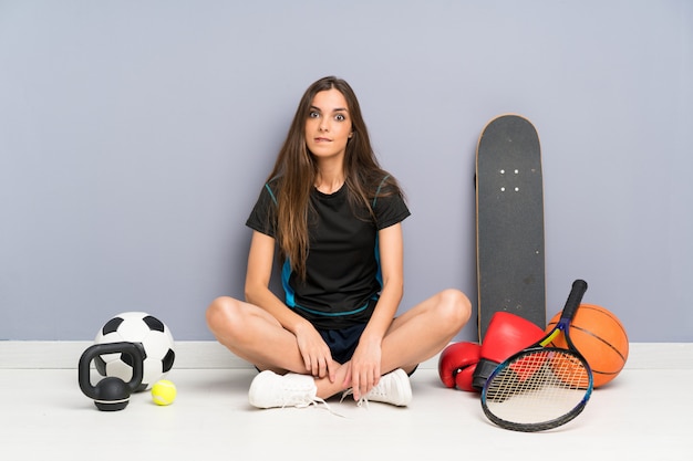 Foto junge sportfrau, die auf dem boden hat zweifel und mit verwirren gesichtsausdruck sitzt