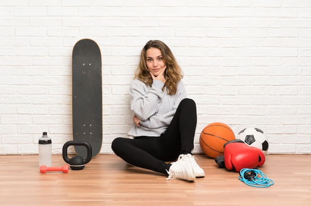 Junge Sportfrau, die auf dem Bodenlachen sitzt