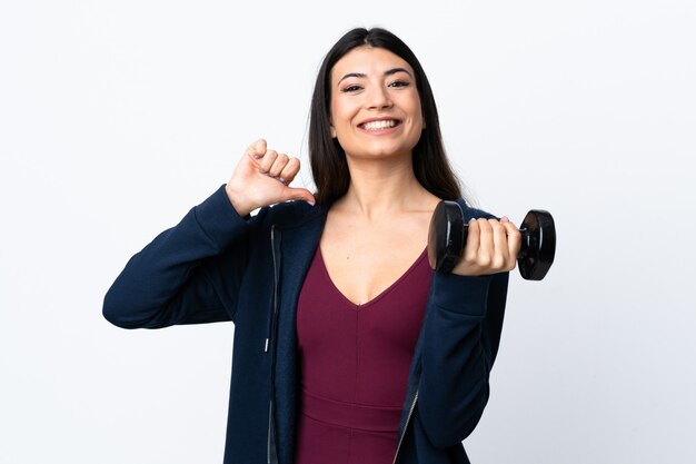 Junge Sportfrau, die Gewichtheben über isolierte weiße Wand stolz und selbstzufrieden macht