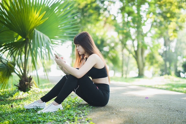 Junge Sportfrau, die Mobile im Park verwendet