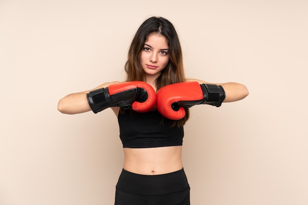 Junge Sportfrau mit Boxhandschuhen über Wand