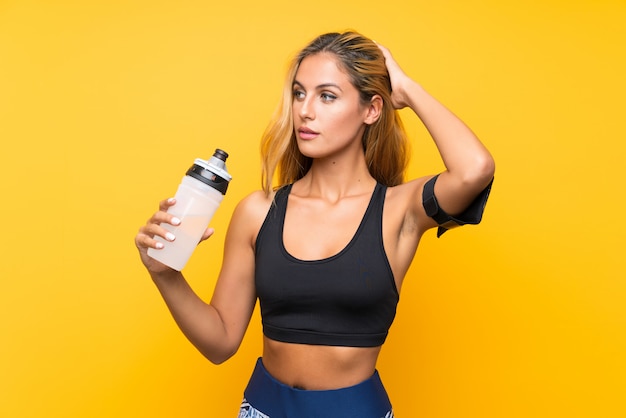 Junge Sportfrau mit einer Flasche Wasser über lokalisierter Wand