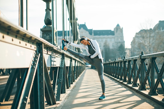 Junge Sportlerin, die ausdehnt und sich vorbereitet zu laufen