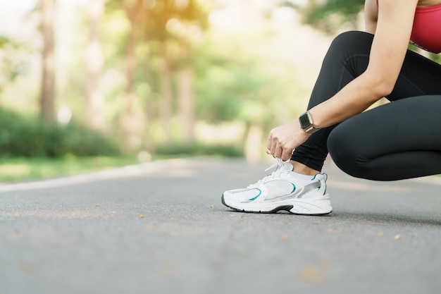 Junge Sportlerin, die Laufschuhe im Park bindet Outdoor-Läuferin bereit zum Joggen auf der Straße außerhalb der asiatischen Fitness Walking und Bewegung auf dem Fußweg in morgendlichen Wellness- und Sportkonzepten