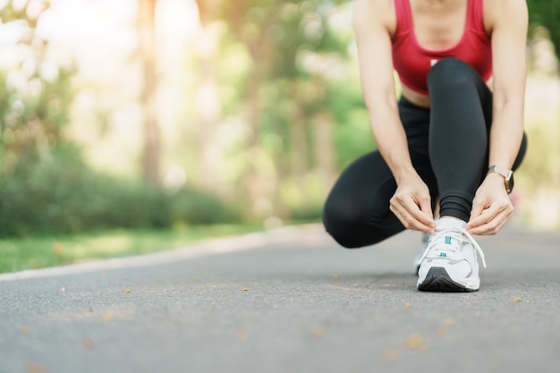 Junge Sportlerin, die Laufschuhe im Park bindet Outdoor-Läuferin bereit zum Joggen auf der Straße außerhalb der asiatischen Fitness Walking und Bewegung auf dem Fußweg in morgendlichen Wellness- und Sportkonzepten