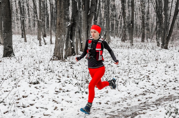 Junge Sportlerin in roten Leggings läuft im Winterwald Wintersport Extremes Laufen