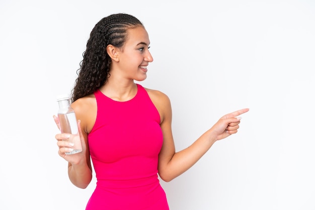 Junge Sportlerin mit einer Flasche Wasser isoliert auf Weiß, die zur Seite zeigt, um ein Produkt zu präsentieren