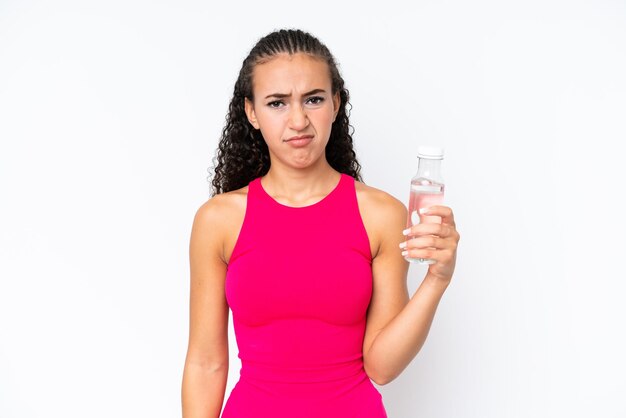 Junge Sportlerin mit einer Flasche Wasser isoliert auf weiß mit traurigem Ausdruck