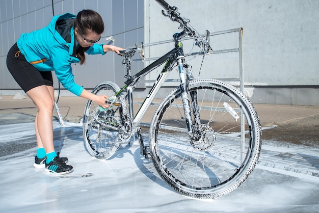 Junge Sportlerin wäscht Fahrrad bei Selbstbedienungsautowäsche