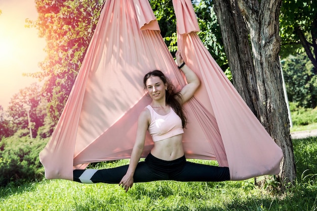 Junge sportlich ausgebildete Yogatrainerin trainiert im Freien unter einem Baum
