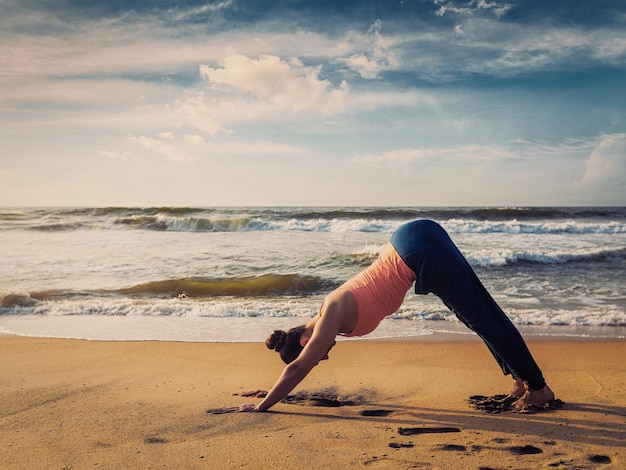 Foto junge, sportlich fitte frau macht yoga im freien am tropischen strand