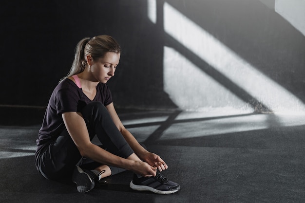 Junge sportliche Frau bereiten sich auf das Training vor. Mädchen, das Schnürsenkel bindet.