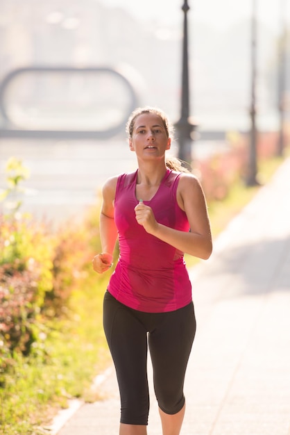 Junge sportliche Frau, die am sonnigen Morgen in der Stadt joggt