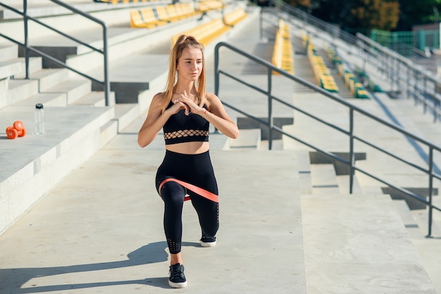 Junge sportliche Frau, die Übungen mit Gummiband im Freien tut