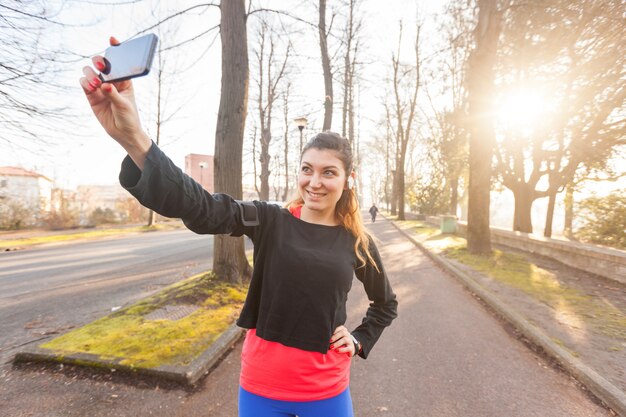 Junge sportliche Frau, die ein Selfie am Park nimmt