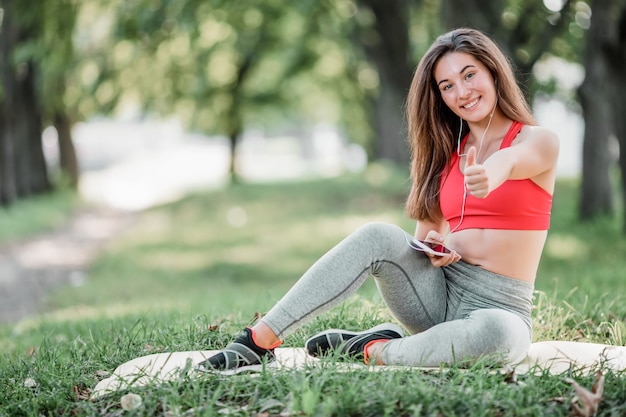 Foto junge sportliche frau, die im park nach dem training ruht