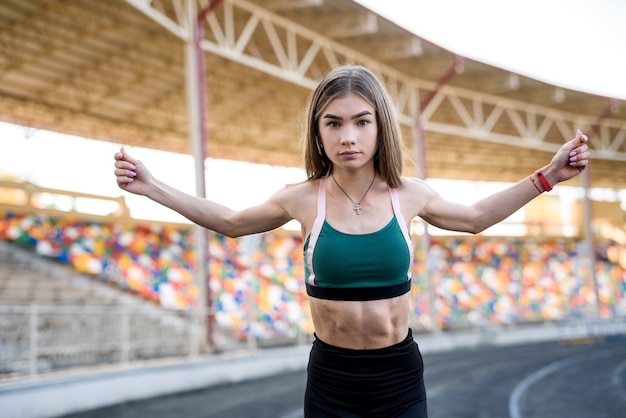 Junge sportliche Frau, die Morgenübungen im Freien auf dem Stadion macht