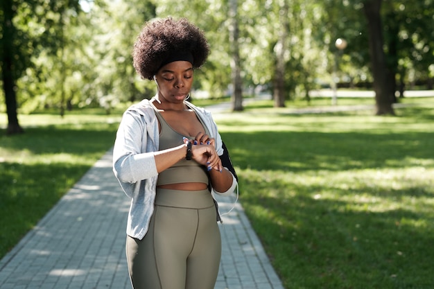 Junge sportliche Frau, die Smartwatch am Handgelenk betrachtet