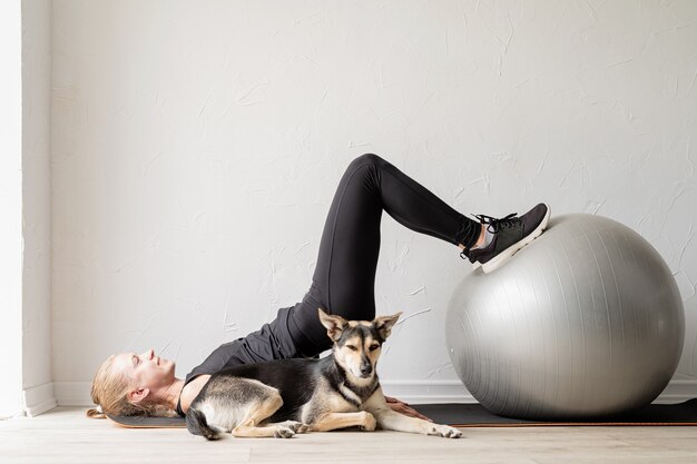 Junge sportliche Frau, die zu Hause auf dem Fitnessball trainiert