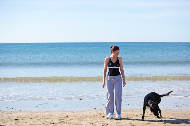 Junge sportliche Frau mit einem Hund auf dem Strand