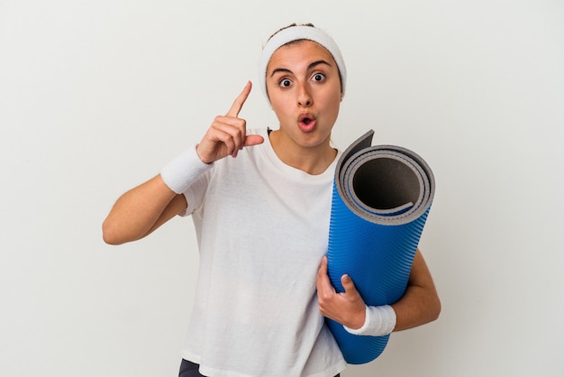 Junge sportliche Frau mit einer Matte isoliert auf weißem Hintergrund mit einer Idee, Inspirationskonzept.